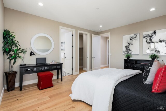 bedroom featuring light wood-type flooring and a walk in closet