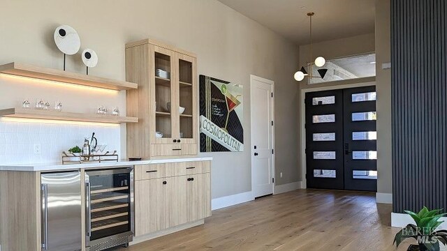 interior space featuring light wood-type flooring, french doors, wine cooler, and indoor bar