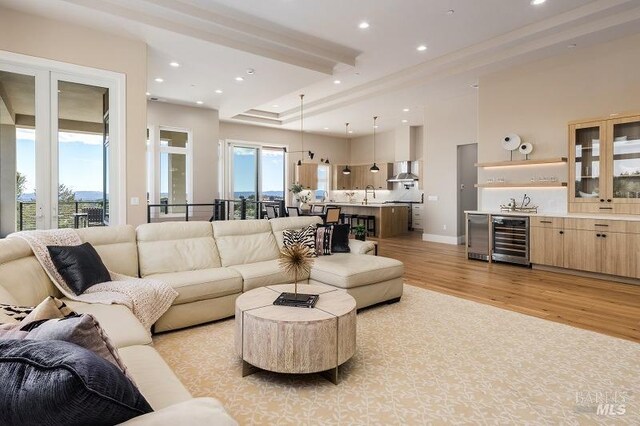 living room featuring wine cooler, light wood-type flooring, and beam ceiling