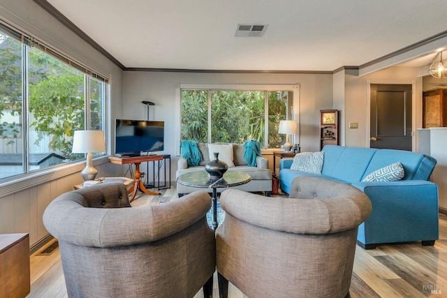 living room with ornamental molding, a wealth of natural light, and light hardwood / wood-style floors