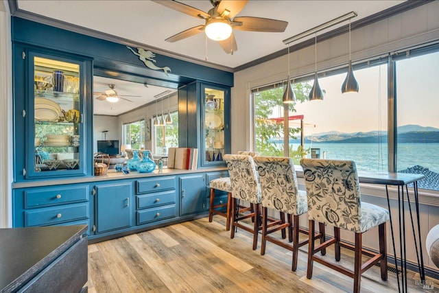 dining area with ceiling fan, light hardwood / wood-style flooring, plenty of natural light, and a water view