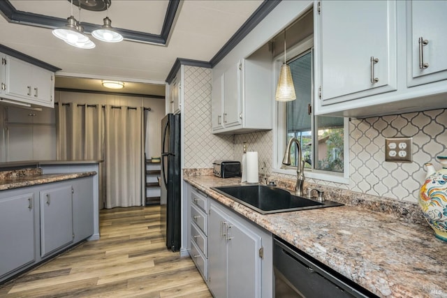 kitchen featuring sink, decorative light fixtures, light hardwood / wood-style flooring, crown molding, and black refrigerator