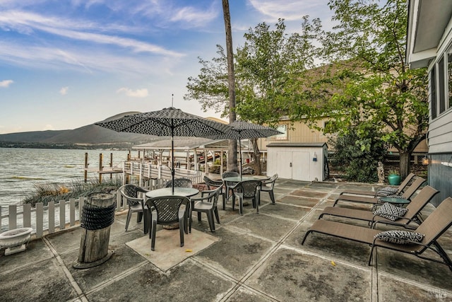 view of patio / terrace featuring a storage shed and a water and mountain view