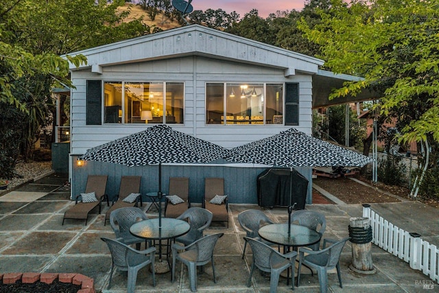 back house at dusk with a patio area