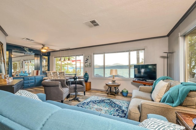 living room featuring a textured ceiling, ceiling fan, hardwood / wood-style flooring, and crown molding