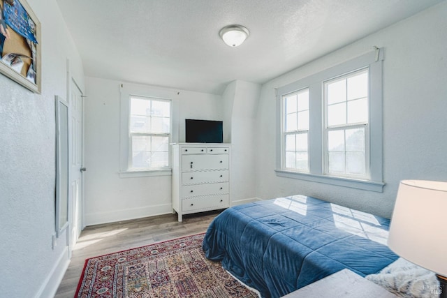 bedroom with a textured ceiling, hardwood / wood-style floors, and multiple windows