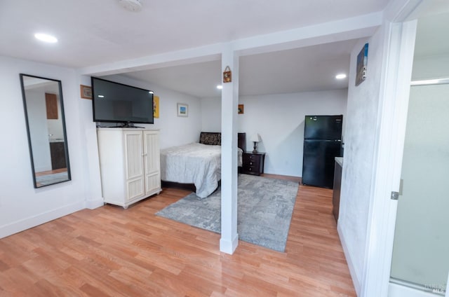 bedroom with black refrigerator and light hardwood / wood-style floors