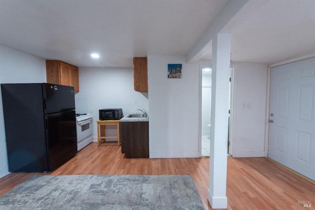 kitchen featuring black appliances, sink, and light hardwood / wood-style flooring