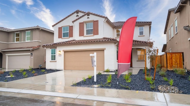 mediterranean / spanish-style home with stucco siding, a tile roof, fence, concrete driveway, and an attached garage