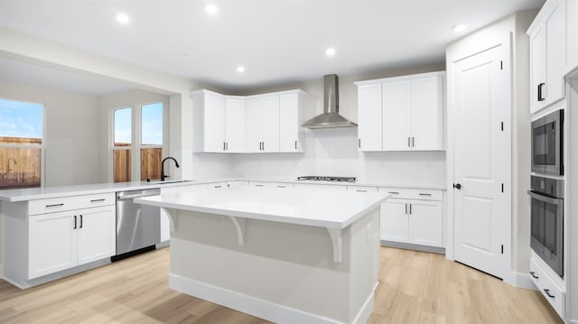 kitchen featuring white cabinetry, a kitchen island, stainless steel appliances, and wall chimney exhaust hood