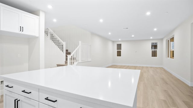 interior space with light wood-type flooring, a center island, and white cabinetry