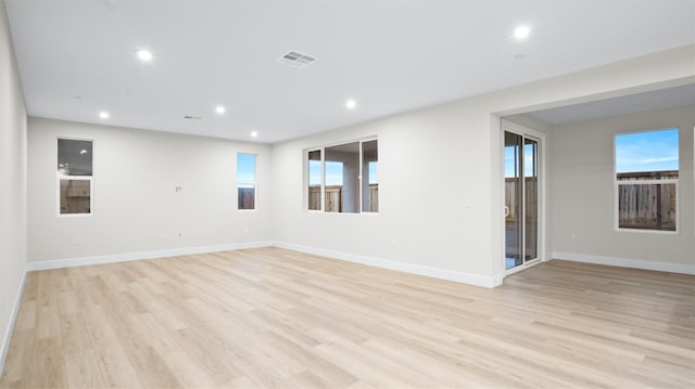 empty room with a wealth of natural light and light hardwood / wood-style flooring