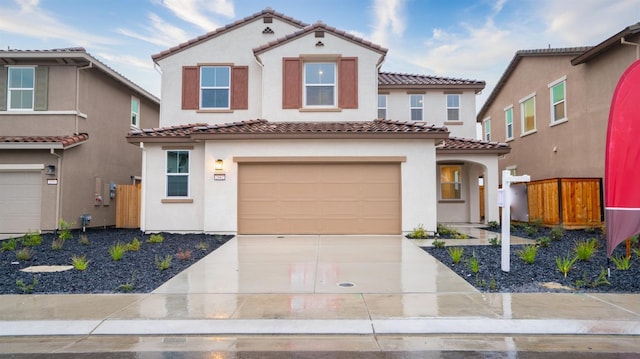 mediterranean / spanish house featuring a tile roof, driveway, and stucco siding