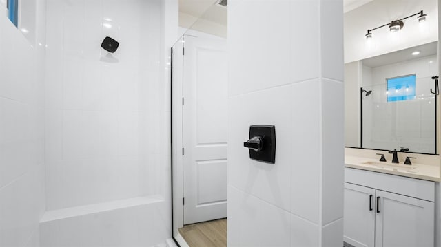 bathroom with a tile shower, vanity, and hardwood / wood-style floors