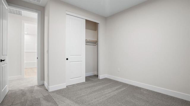 unfurnished bedroom featuring light colored carpet and a closet