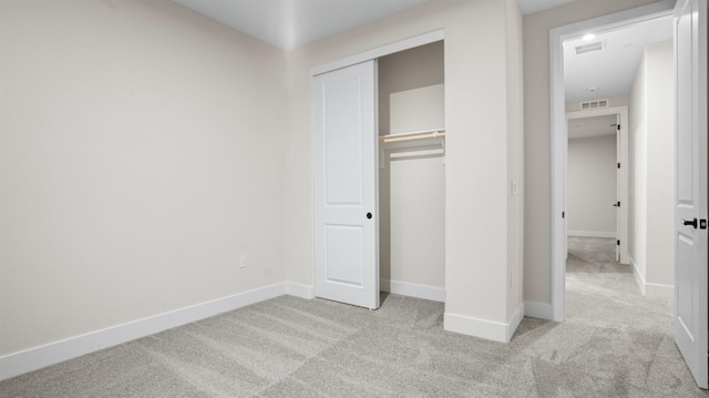 unfurnished bedroom featuring light carpet and a closet