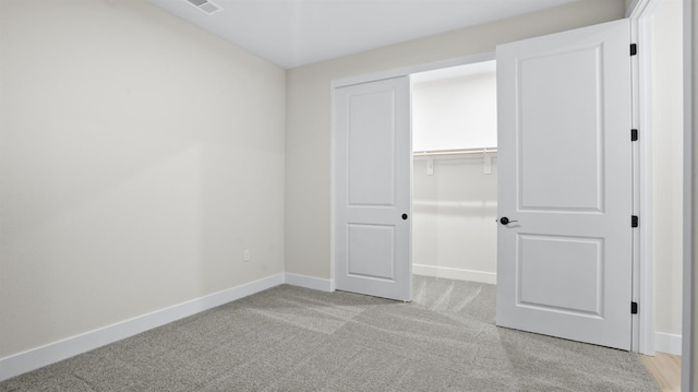 unfurnished bedroom with a closet and light colored carpet