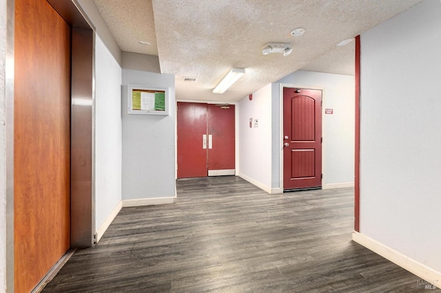 hall featuring dark wood-type flooring and a textured ceiling