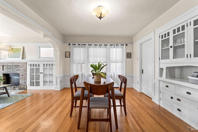 dining area with light hardwood / wood-style floors and a brick fireplace