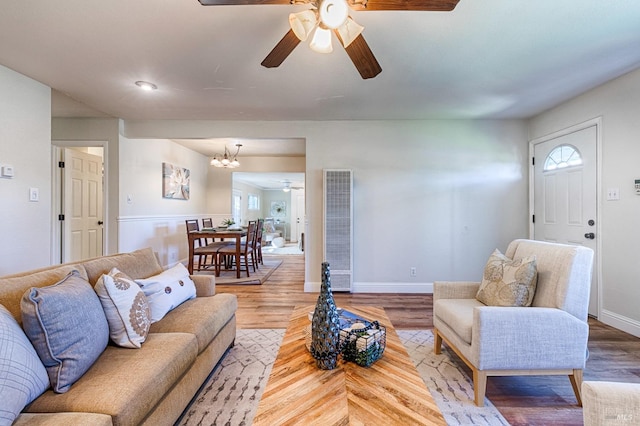 living room with ceiling fan with notable chandelier and wood-type flooring