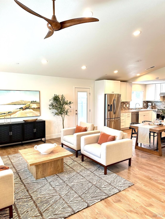 living room featuring vaulted ceiling, sink, ceiling fan, and light hardwood / wood-style floors