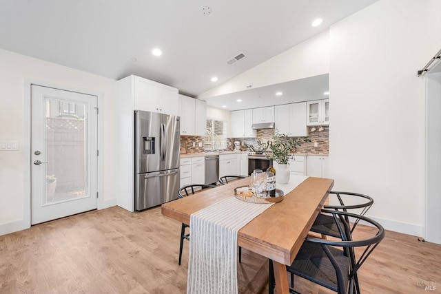 kitchen with white cabinetry, appliances with stainless steel finishes, vaulted ceiling, and tasteful backsplash