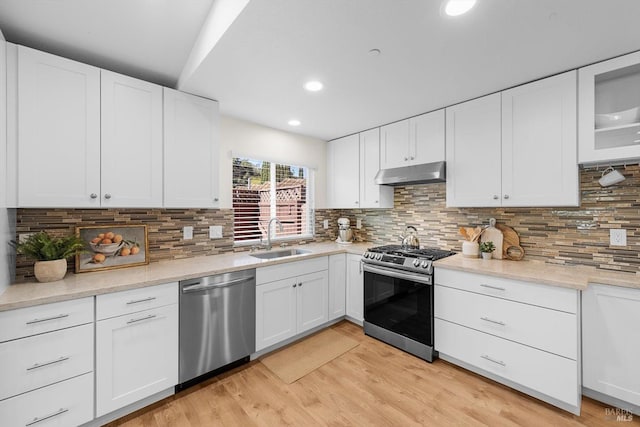 kitchen with sink, light wood-type flooring, white cabinets, and appliances with stainless steel finishes