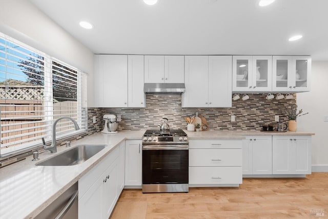 kitchen featuring sink, white cabinetry, tasteful backsplash, light wood-type flooring, and appliances with stainless steel finishes