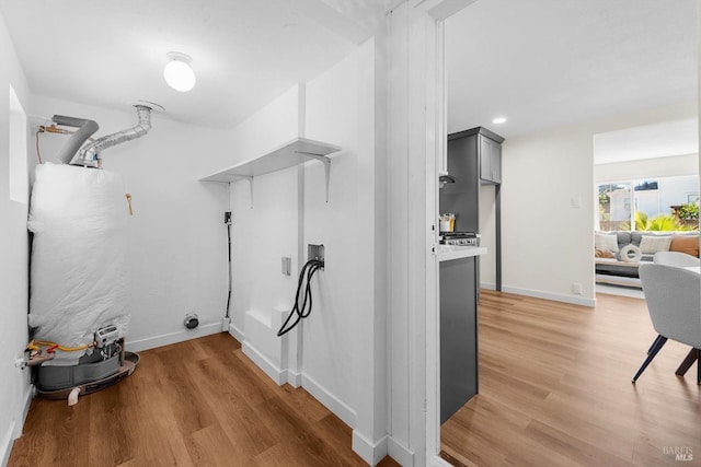 clothes washing area featuring hookup for a washing machine, gas water heater, and light hardwood / wood-style flooring