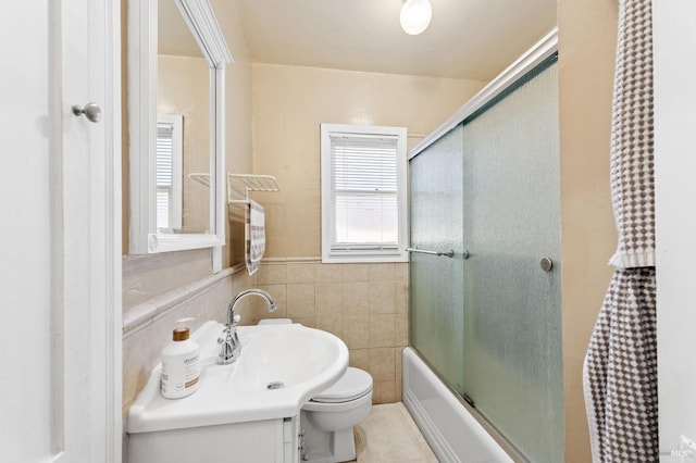 full bathroom featuring enclosed tub / shower combo, tile walls, vanity, and toilet