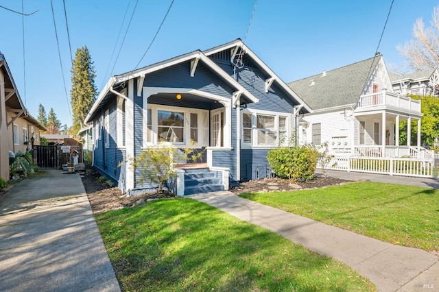 bungalow-style home with a balcony and a front lawn