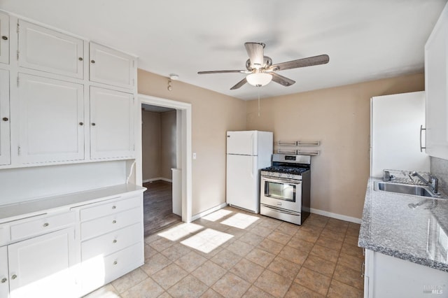 kitchen with sink, white cabinetry, white refrigerator, stainless steel range with gas cooktop, and ceiling fan