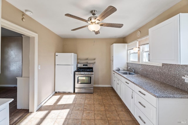 kitchen featuring sink, stainless steel range with gas cooktop, white fridge, decorative backsplash, and white cabinets