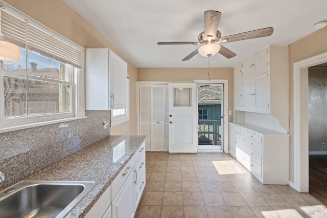 kitchen featuring sink, white cabinets, decorative backsplash, ceiling fan, and light stone countertops