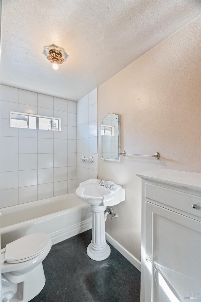 bathroom featuring tiled shower / bath, toilet, and a textured ceiling