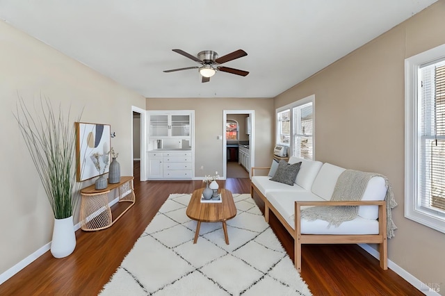 living room with built in shelves, baseboards, a ceiling fan, and wood finished floors