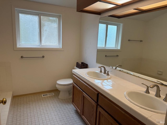 bathroom with tile patterned floors, vanity, a healthy amount of sunlight, and toilet