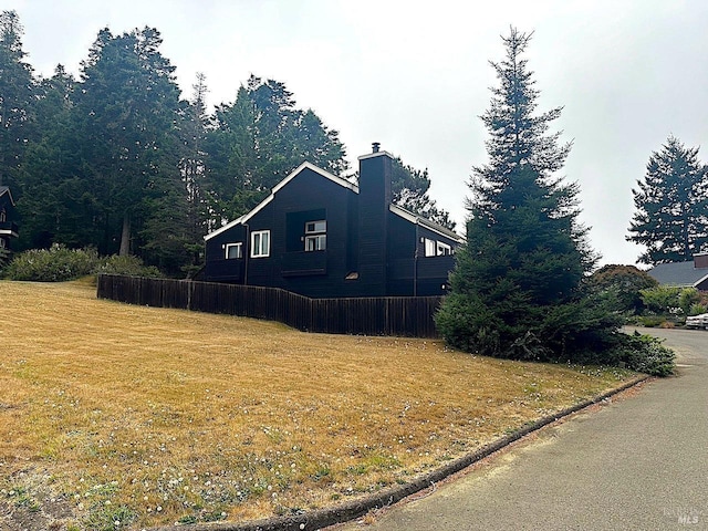 view of property exterior featuring a chimney and a yard