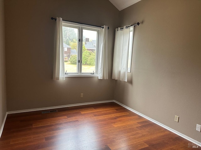 unfurnished room featuring dark hardwood / wood-style flooring and vaulted ceiling