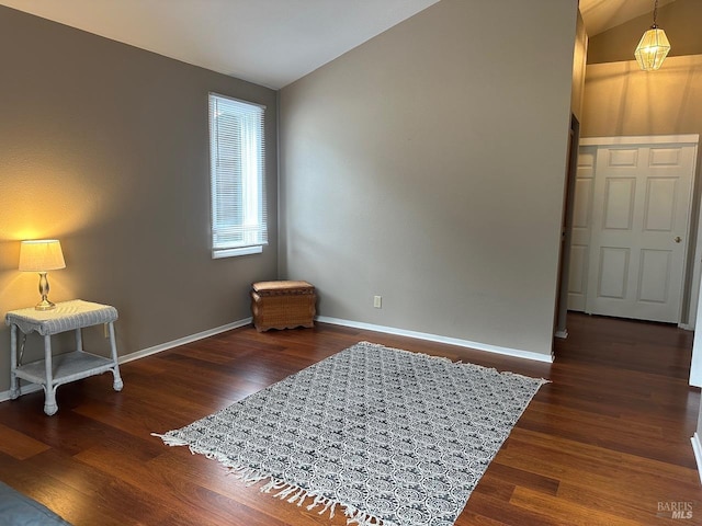 interior space featuring lofted ceiling, wood finished floors, and baseboards