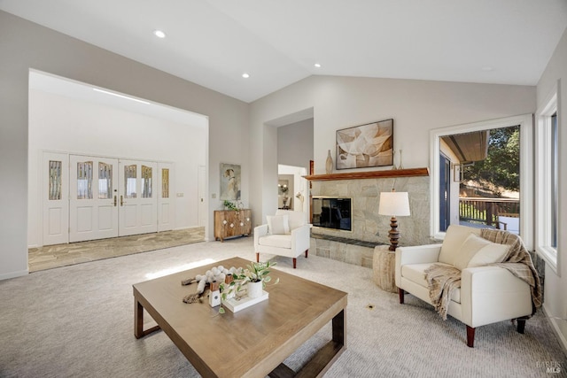 living room featuring a tiled fireplace, light colored carpet, and vaulted ceiling