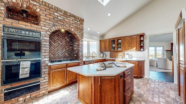 kitchen featuring a center island, sink, stainless steel gas cooktop, high vaulted ceiling, and black double oven