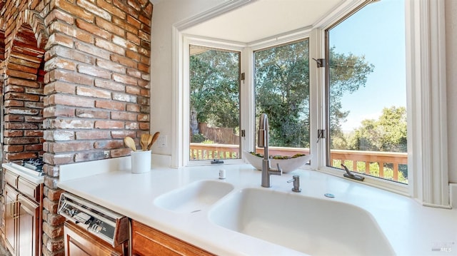 kitchen with dishwashing machine, brick wall, plenty of natural light, and sink