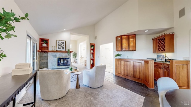 living room with a stone fireplace and high vaulted ceiling