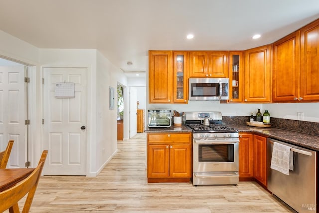 kitchen featuring stainless steel appliances, dark stone countertops, and light hardwood / wood-style floors