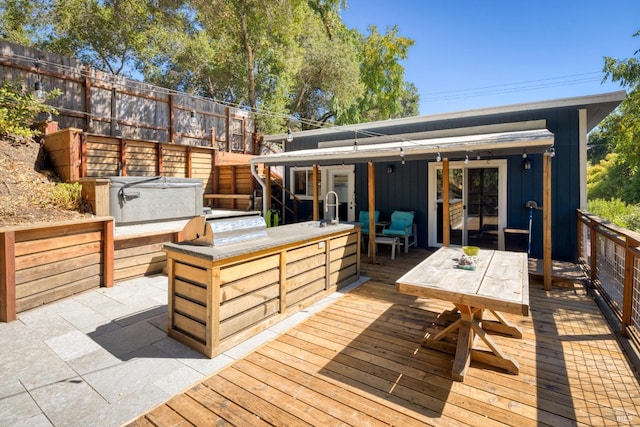 wooden terrace with a hot tub, area for grilling, and sink