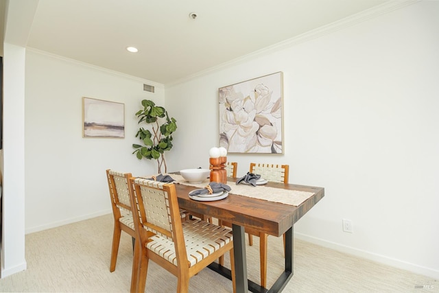 dining room with ornamental molding and light carpet