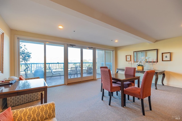 carpeted dining space featuring plenty of natural light and beamed ceiling