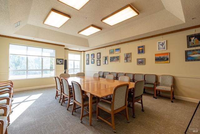 carpeted dining room with a tray ceiling and a textured ceiling