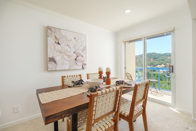 dining area featuring ornamental molding and light carpet